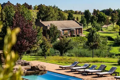 a house with lounge chairs and a swimming pool at Gooderson Kloppenheim Country Estate in Machadodorp