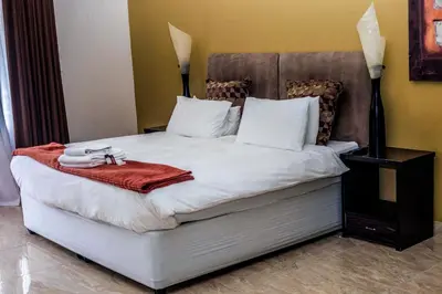 a bed with white sheets and a red blanket at Coyotes Hotel & Conference Centre in Nelspruit