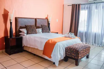 a bedroom with a bed and a chair and a window at Coyotes Hotel & Conference Centre in Nelspruit