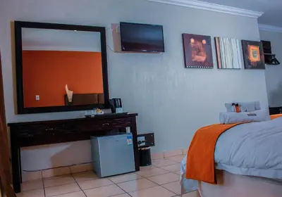 a bedroom with a bed and a television on the wall at Coyotes Hotel & Conference Centre in Nelspruit