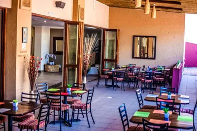 a restaurant with tables and chairs in a room at Coyotes Hotel & Conference Centre in Nelspruit