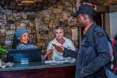 a man standing at a counter talking to a woman at Coyotes Hotel & Conference Centre in Nelspruit