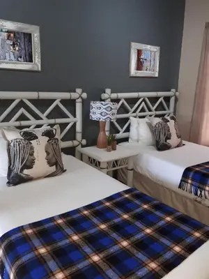 a bedroom with two beds and a table at Blue Grass Nest in Nelspruit