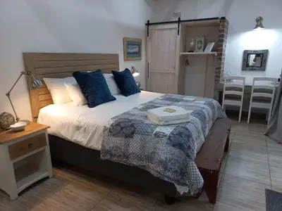 a bedroom with a large bed with blue pillows at Klipkoppie Cottage in Nelspruit