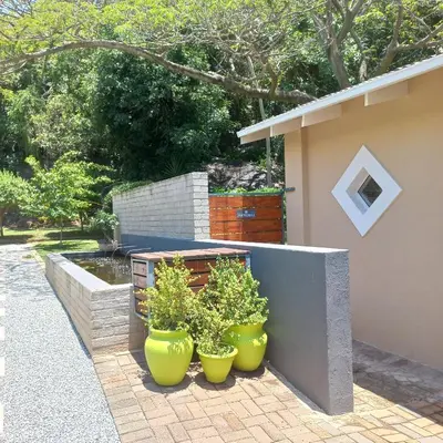 three green pots with plants in them next to a building at Klipkoppie Cottage in Nelspruit