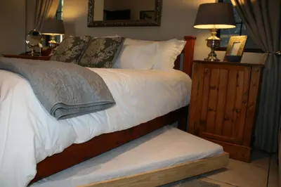 a bedroom with a bed with white sheets and pillows at Klipkoppie Cottage in Nelspruit