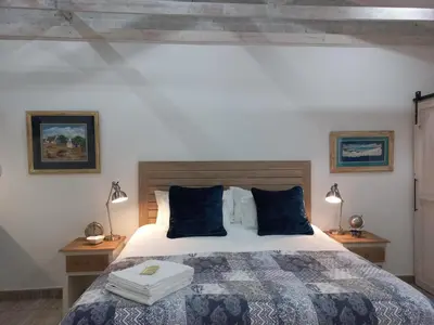 a bedroom with a large bed with blue pillows at Klipkoppie Cottage in Nelspruit