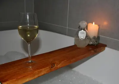 a glass of wine and a candle on a bath tub at Klipkoppie Cottage in Nelspruit