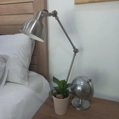 a lamp and a plant on a table next to a bed at Klipkoppie Cottage in Nelspruit