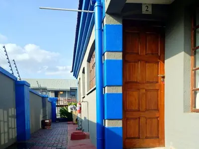 a blue and white building with a wooden door at Elegant Guest House Malelane in Malelane