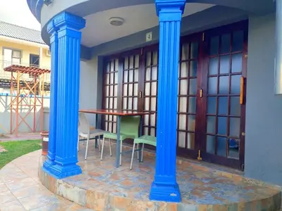a patio with blue columns and a table and chairs at Elegant Guest House Malelane in Malelane