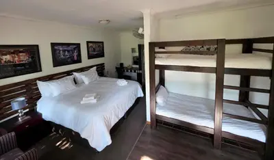 a bedroom with two bunk beds with white sheets at Wayside Lodge in Waterval Boven