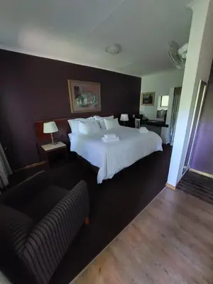 a hotel room with a large bed and a couch at Wayside Lodge in Waterval Boven