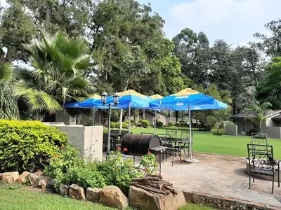 a patio with tables and blue umbrellas at Wayside Lodge in Waterval Boven