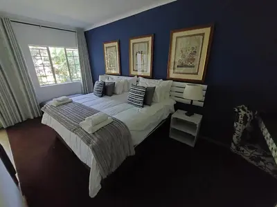 a bedroom with a large bed and a blue wall at Wayside Lodge in Waterval Boven