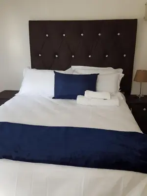a large bed with blue and white sheets and pillows at MZET GUEST HOUSE in Ermelo