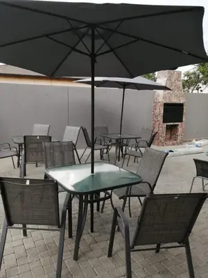 a group of tables and chairs with an umbrella at MZET GUEST HOUSE in Ermelo