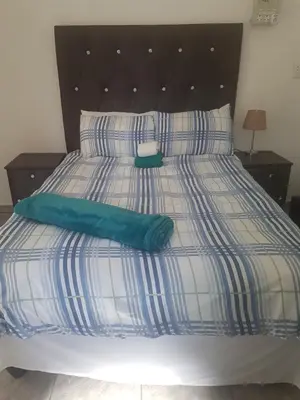 a bed with a blue and white comforter and pillows at MZET GUEST HOUSE in Ermelo