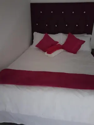 a bed with two red pillows on top of it at MZET GUEST HOUSE in Ermelo