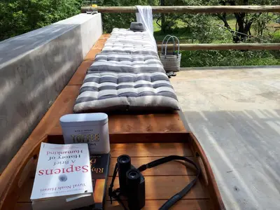 a bench on a deck with a book and a camera at Kruger Willows in Marloth Park