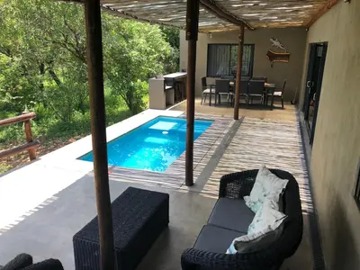 a patio with a swimming pool and a table and chairs at Kruger Willows in Marloth Park