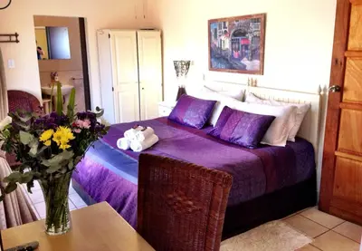 a bedroom with a purple bed with a vase of flowers at Pilgrims Delight Guest House in Centurion