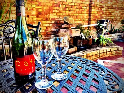 two wine glasses and a bottle on a table at Pilgrims Delight Guest House in Centurion