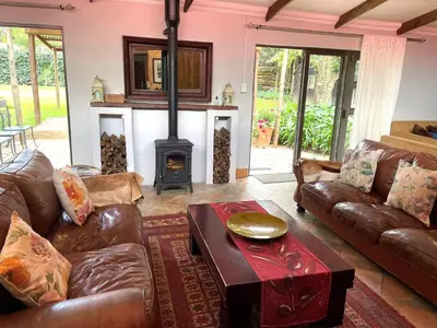 a living room with leather couches and a wood stove at Van De Poll House in Dullstroom