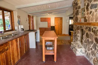 a kitchen with a table and a stone fireplace at Van De Poll House in Dullstroom