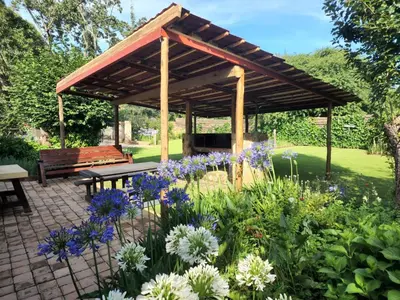 a pavilion with a bench and flowers in a garden at Van De Poll House in Dullstroom