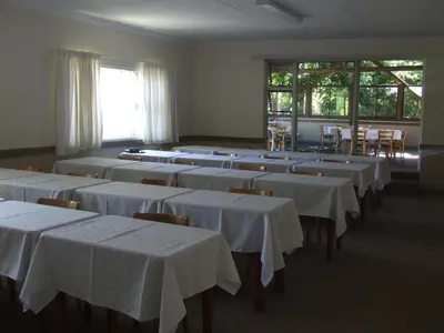 a room with rows of tables and chairs with white linens at Dove's Nest Guest House in Kempton Park