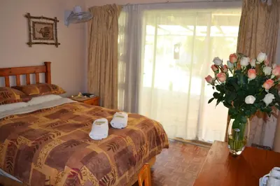 a bedroom with a bed and a vase of flowers at Dove's Nest Guest House in Kempton Park