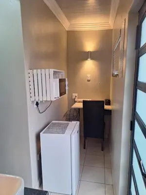 a small kitchen with a white refrigerator and a desk at 9 Levubu Cottages in Polokwane