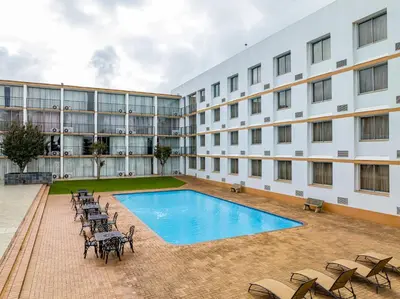 a large building with a swimming pool and chairs at African Sky Ermelo Inn in Ermelo