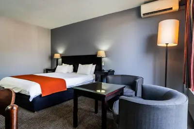 a hotel room with a bed and a chair at African Sky Ermelo Inn in Ermelo