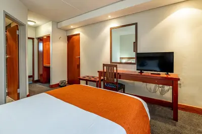 a hotel room with a bed and a desk with a television at African Sky Ermelo Inn in Ermelo