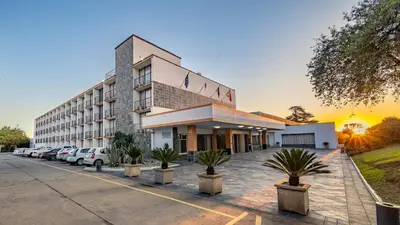 a hotel with cars parked in a parking lot at African Sky Ermelo Inn in Ermelo