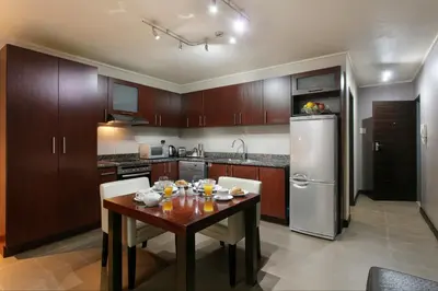 a kitchen with a wooden table and a refrigerator at Absolute Farenden Apartments in Pretoria