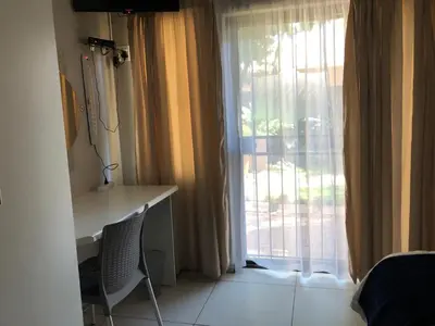a room with a window with a desk and a window with curtains at Odelia Guest House in Mokopane