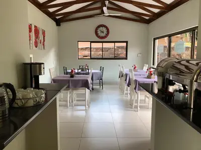 a dining room with purple tables and white chairs at Odelia Guest House in Mokopane
