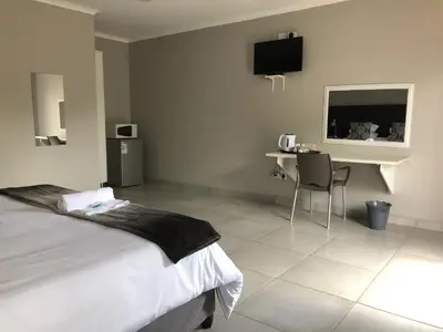a bedroom with a bed and a table and a desk at Odelia Guest House in Mokopane