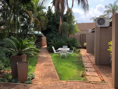 a patio with a table and chairs in a yard at Odelia Guest House in Mokopane