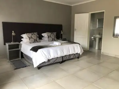 a bedroom with a large bed with a black headboard at Odelia Guest House in Mokopane