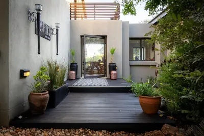 a house with a wooden porch with potted plants at Rafiki Bush Lodge in Hoedspruit