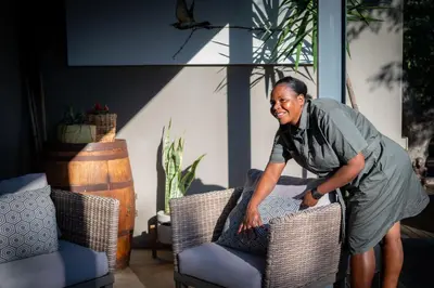 a woman is standing next to two chairs at Rafiki Bush Lodge in Hoedspruit