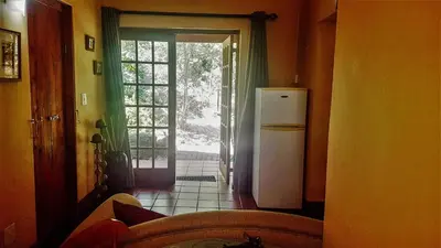 a kitchen with a refrigerator and an open door at Raka Cottage in Nelspruit