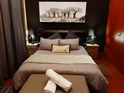 a bedroom with a bed with two towels on a table at Raka Cottage in Nelspruit