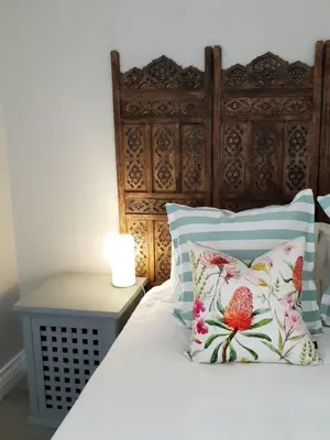 a bed with a wooden headboard and pillows at NOOii - Flatlet in Pretoria