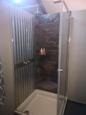 a shower with a glass door in a bathroom at Treur River Lodge in Moremela