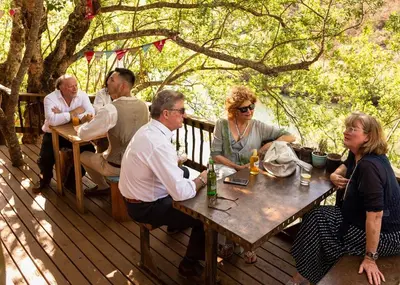 a group of people sitting at a table on a deck at Treur River Lodge in Moremela